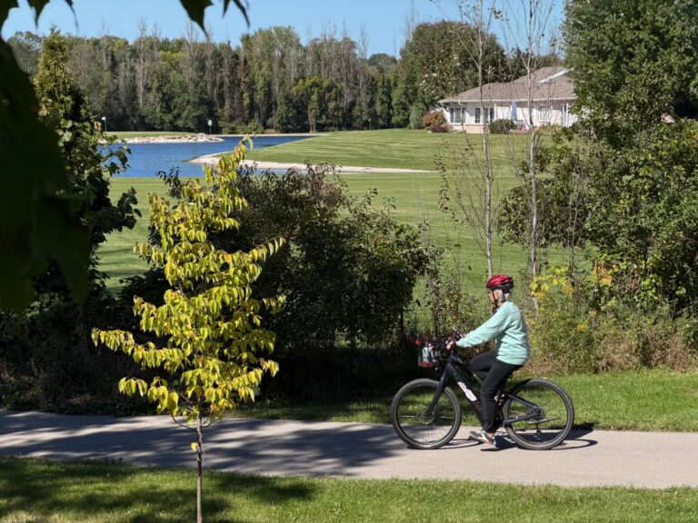 Person riding bike path with River Pines in the background